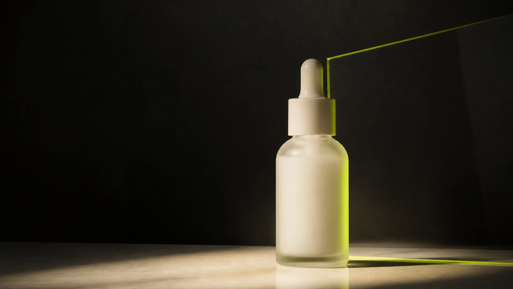 An unbranded glass dropper bottle lit in a dark studio